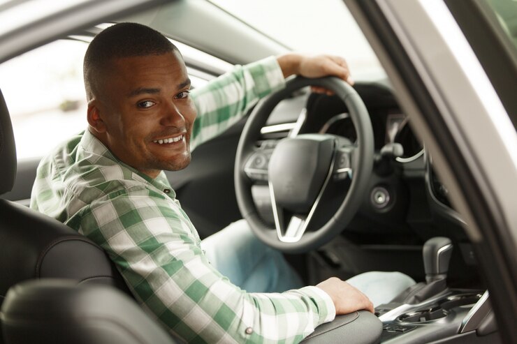 cheerful-african-man-smiling-camera-sitting-his-new-car-dealership_130388-293